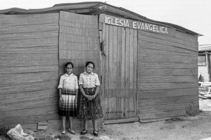 Retrat de dues dones davant d’una barraca de fusta, en un carrer sense asfaltar
